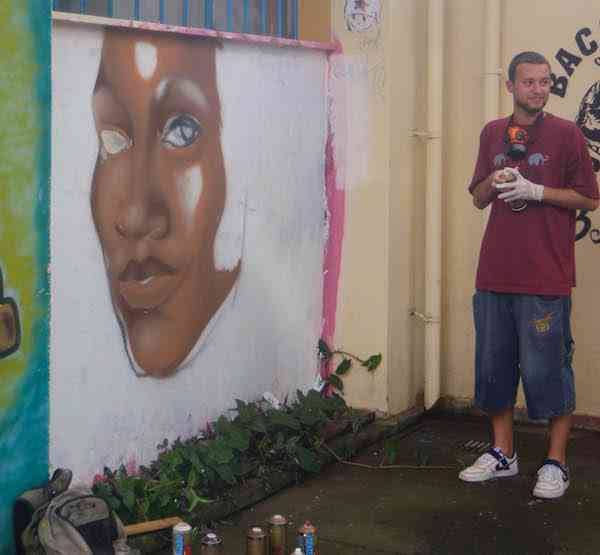 Portrait of an artist finishing his street art on a favela wall.